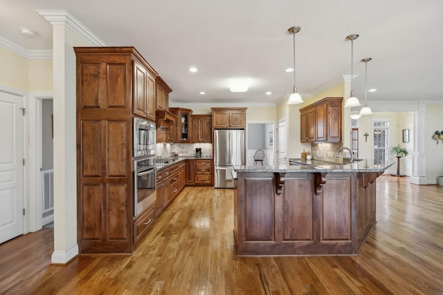 kitchen with appliances with stainless steel finishes, a breakfast bar area, a peninsula, glass insert cabinets, and light stone countertops