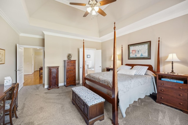 bedroom featuring light carpet, ensuite bathroom, a tray ceiling, crown molding, and ceiling fan