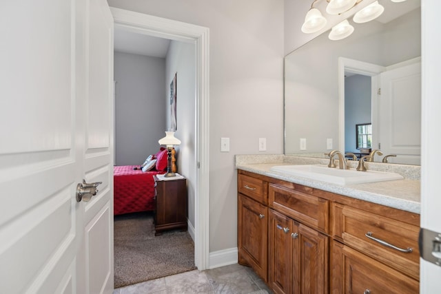 ensuite bathroom featuring vanity, baseboards, ensuite bath, tile patterned floors, and a notable chandelier