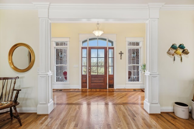 entryway with light wood-type flooring, baseboards, ornamental molding, and ornate columns