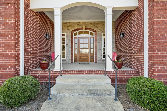 entrance to property featuring brick siding and covered porch