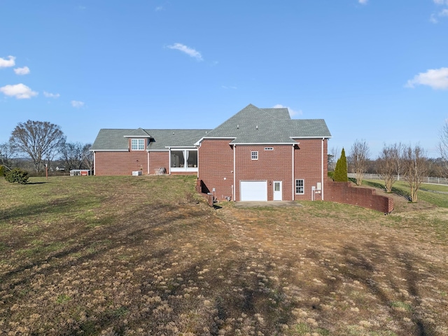 rear view of property with a garage, brick siding, and a yard