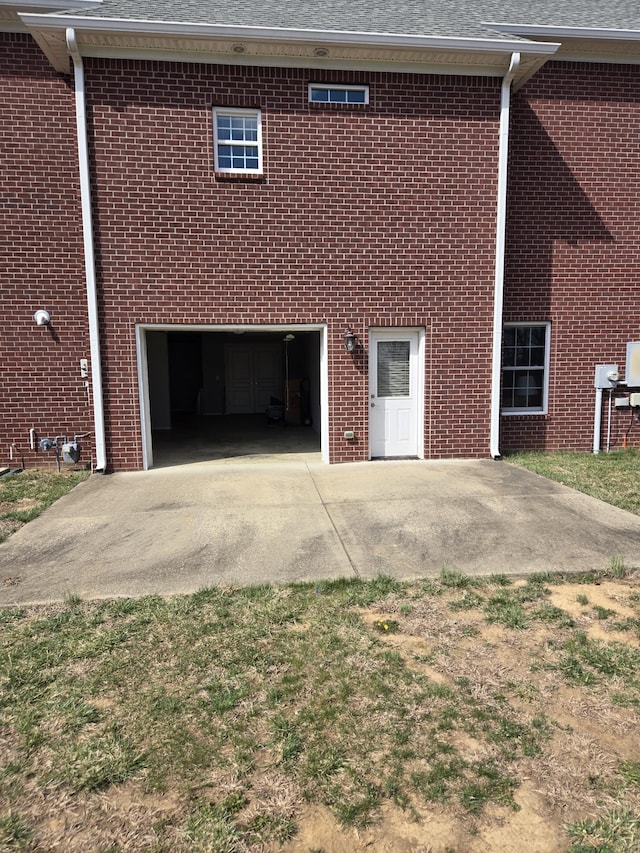 view of side of property featuring brick siding, concrete driveway, an attached garage, and a shingled roof