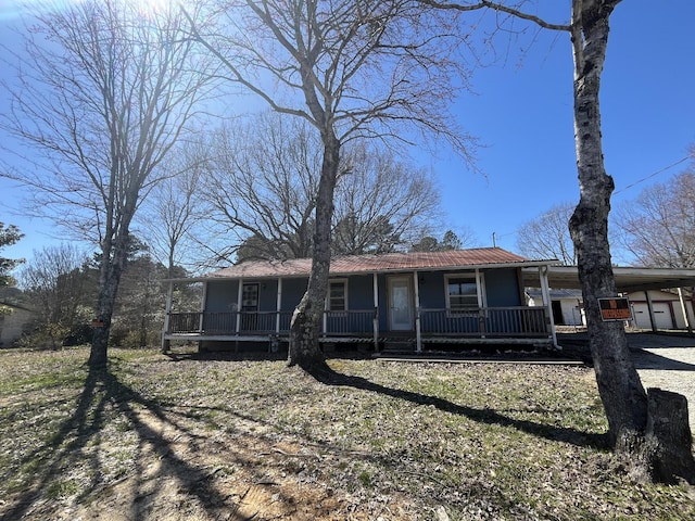 view of front of house with metal roof, a carport, covered porch, and driveway