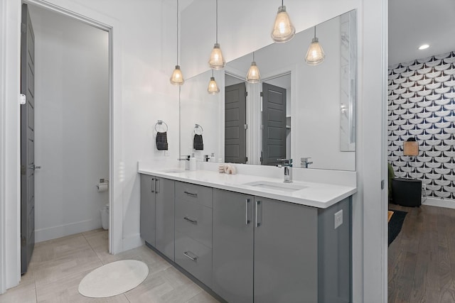 full bath with double vanity, toilet, baseboards, and a sink