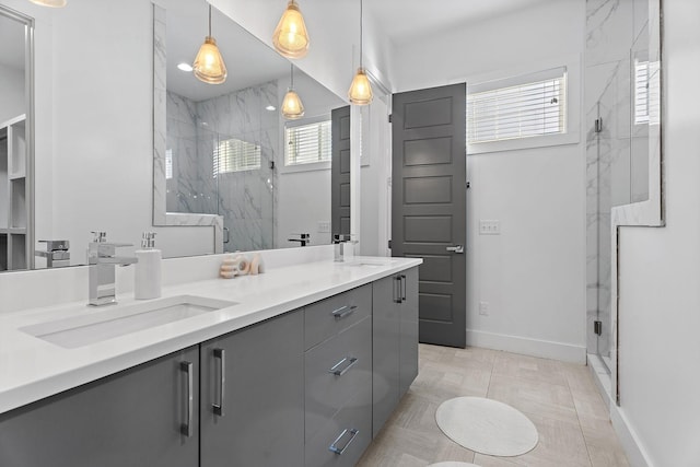 full bathroom featuring a marble finish shower, double vanity, baseboards, and a sink