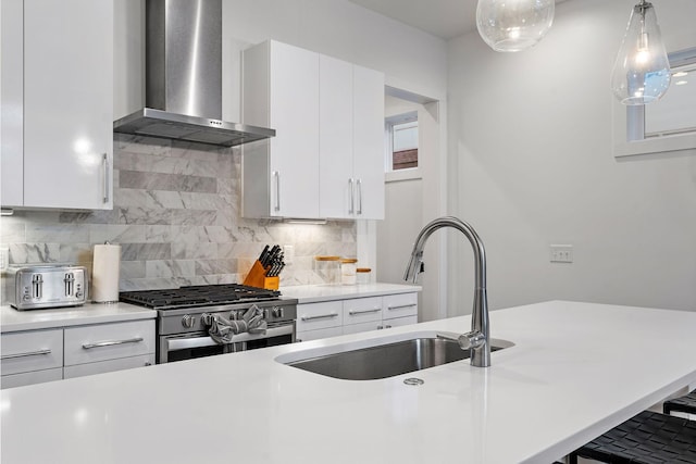 kitchen featuring a sink, light countertops, wall chimney exhaust hood, and high end stove