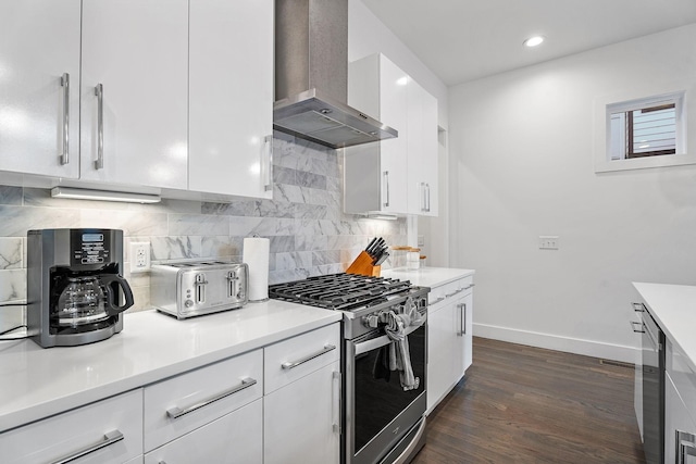 kitchen featuring dark wood finished floors, white cabinetry, stainless steel range with gas cooktop, wall chimney exhaust hood, and light countertops