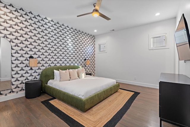 bedroom featuring recessed lighting, an accent wall, baseboards, and wood finished floors