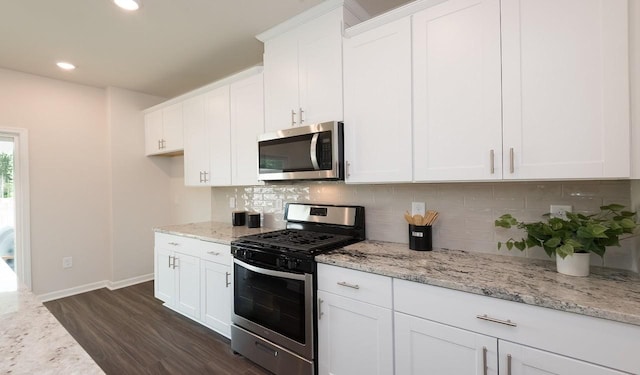 kitchen with stainless steel appliances, backsplash, dark wood finished floors, and white cabinetry