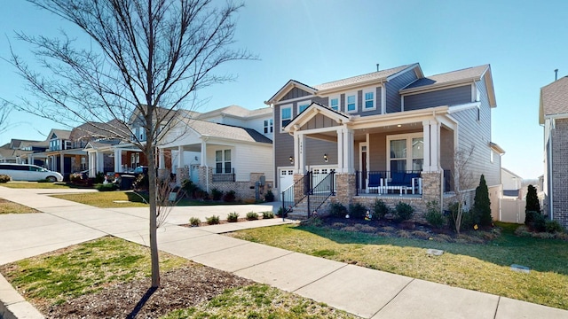 craftsman inspired home with a porch, an attached garage, concrete driveway, a front lawn, and board and batten siding