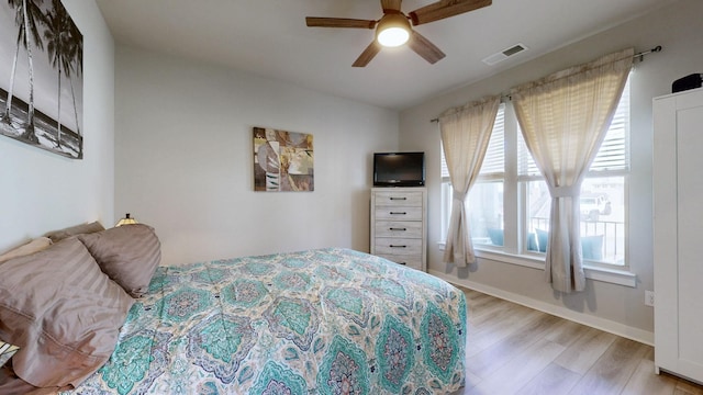 bedroom with ceiling fan, light wood-style floors, visible vents, and baseboards