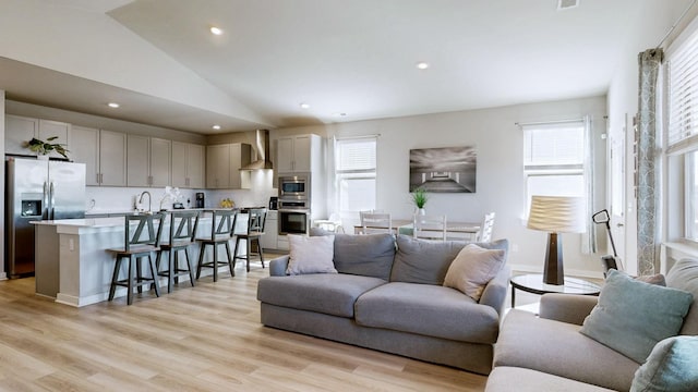 living room featuring recessed lighting, light wood-type flooring, and vaulted ceiling