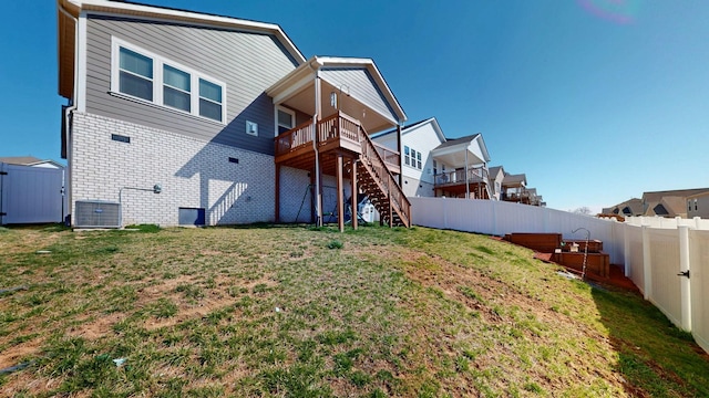 rear view of house featuring fence, stairs, central AC, a lawn, and a deck