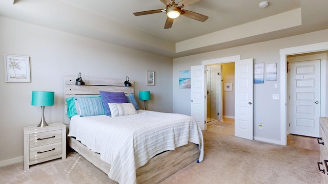 bedroom featuring light carpet, ceiling fan, a raised ceiling, and baseboards