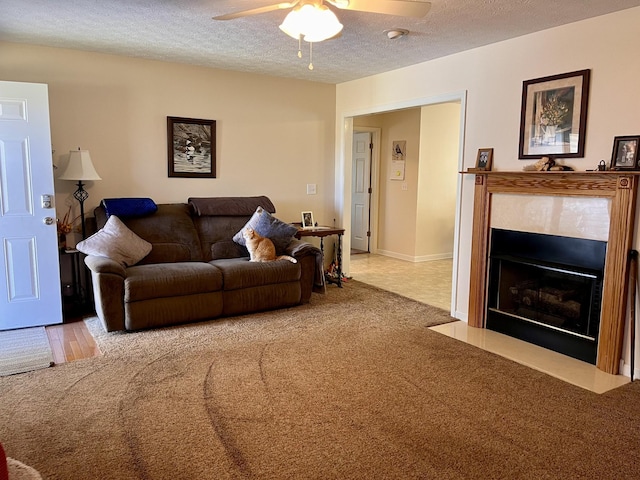 living area featuring carpet flooring, a fireplace with flush hearth, a textured ceiling, and a ceiling fan