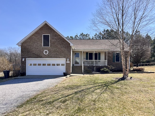 view of front facade with a front lawn, covered porch, gravel driveway, an attached garage, and brick siding