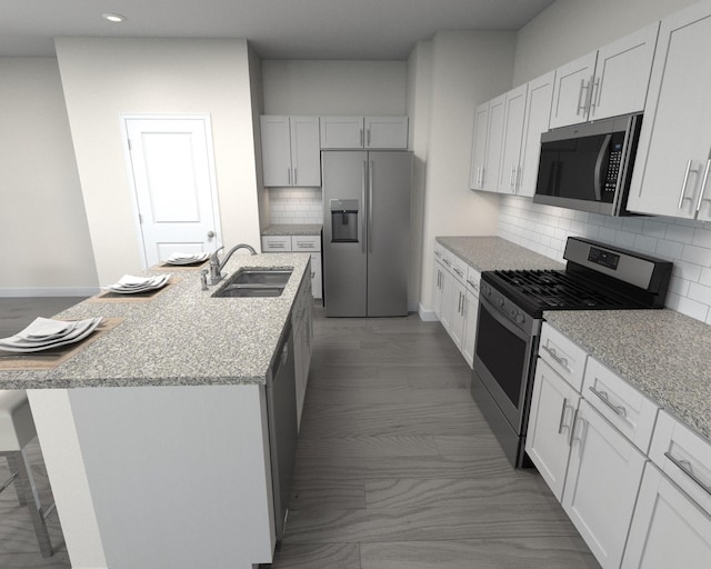 kitchen with light stone countertops, an island with sink, decorative backsplash, stainless steel appliances, and a sink