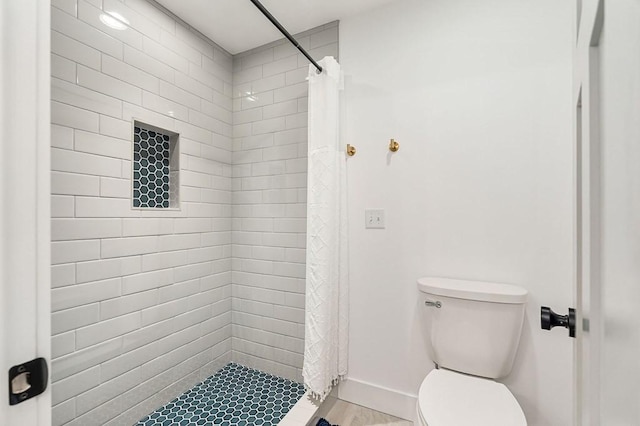 bathroom featuring a stall shower, toilet, and baseboards