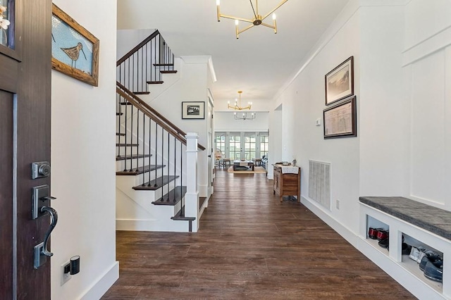 entryway with visible vents, a notable chandelier, wood finished floors, and stairs