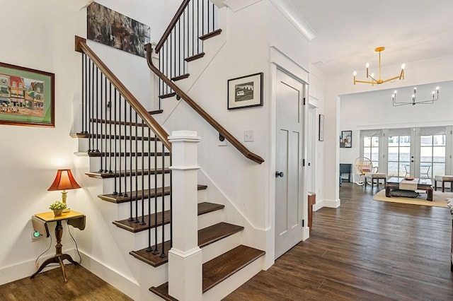 stairway featuring a notable chandelier, french doors, baseboards, and wood finished floors