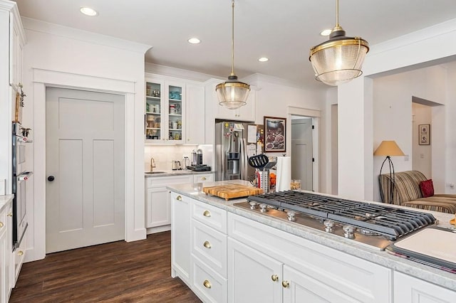 kitchen featuring dark wood finished floors, light countertops, glass insert cabinets, appliances with stainless steel finishes, and decorative light fixtures