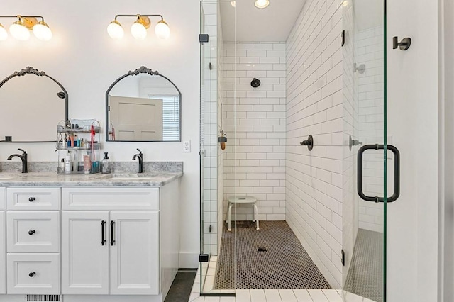 bathroom with double vanity, a stall shower, and a sink