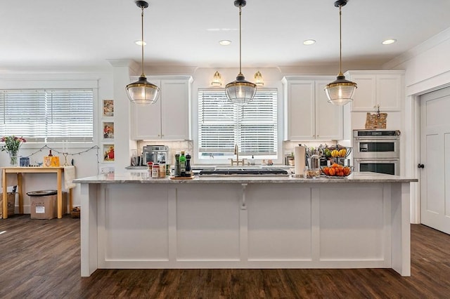 kitchen featuring light stone counters, white cabinets, plenty of natural light, and stainless steel appliances