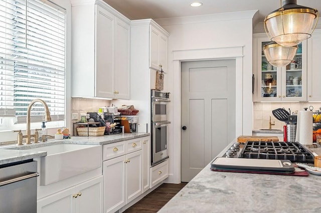 kitchen featuring a sink, backsplash, white cabinetry, appliances with stainless steel finishes, and dark wood-style flooring