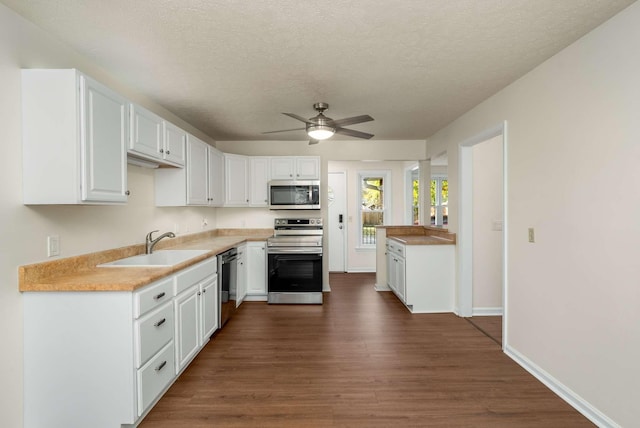 kitchen featuring a sink, stainless steel appliances, dark wood-style floors, and white cabinetry