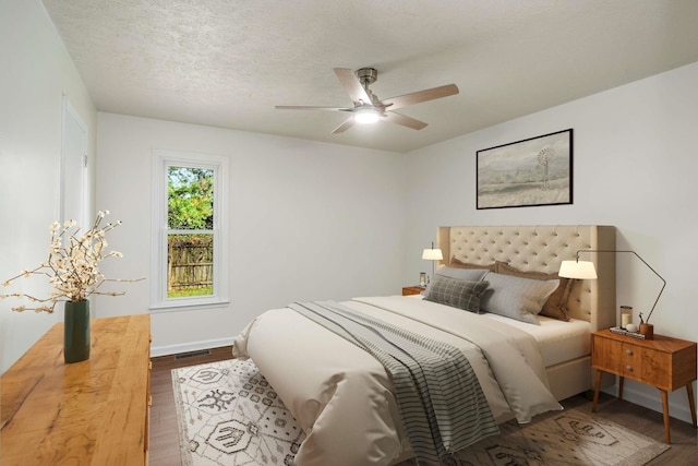 bedroom featuring visible vents, baseboards, ceiling fan, wood finished floors, and a textured ceiling