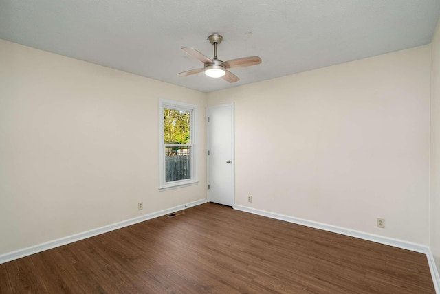 spare room featuring dark wood finished floors, visible vents, ceiling fan, and baseboards