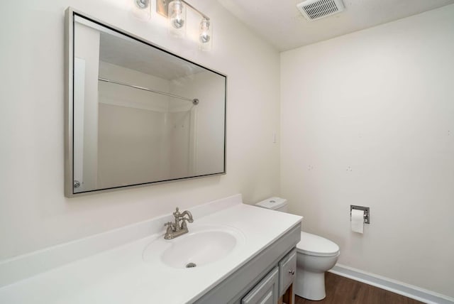 bathroom with visible vents, baseboards, toilet, wood finished floors, and vanity