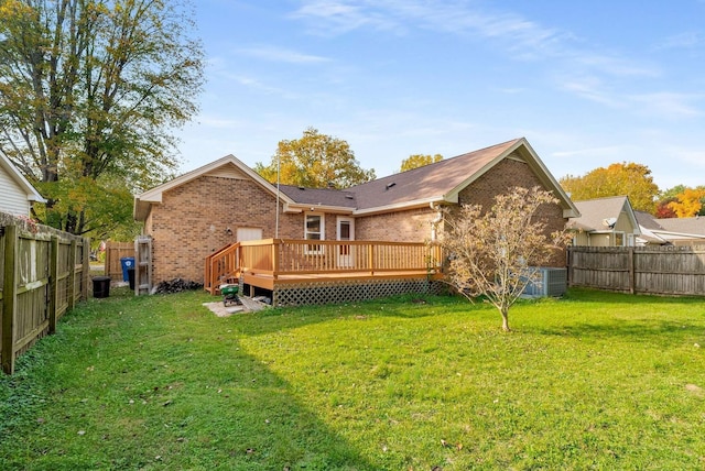 rear view of property with a deck, brick siding, a fenced backyard, and a lawn