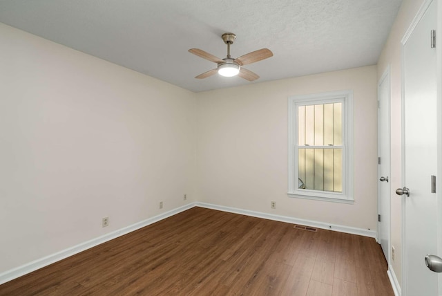 spare room with baseboards, visible vents, ceiling fan, dark wood-type flooring, and a textured ceiling