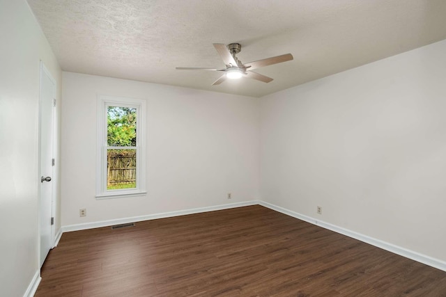 spare room featuring visible vents, a ceiling fan, a textured ceiling, dark wood finished floors, and baseboards