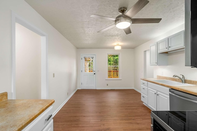 kitchen with dishwasher, light countertops, wood finished floors, a textured ceiling, and a sink