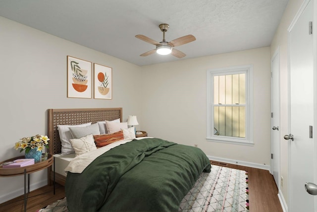 bedroom featuring ceiling fan, baseboards, and wood finished floors