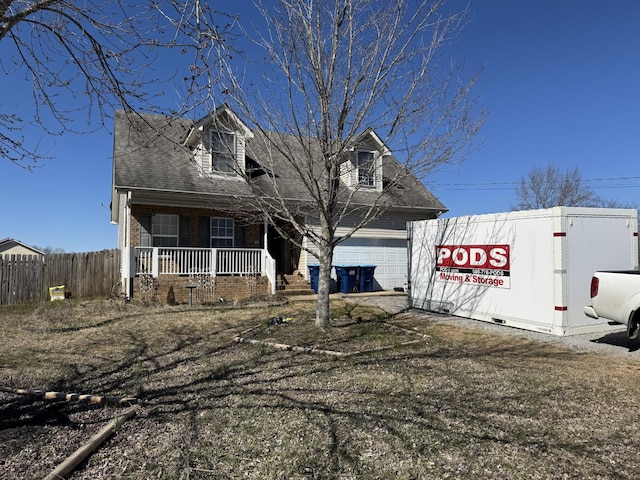 new england style home featuring a garage, roof with shingles, a porch, and fence