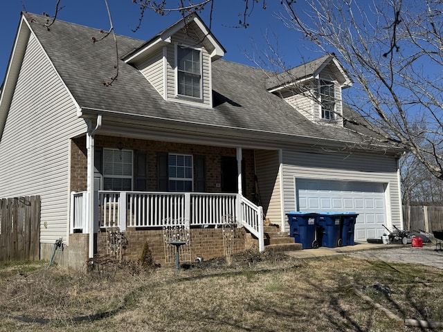 new england style home with fence, a porch, an attached garage, a shingled roof, and brick siding