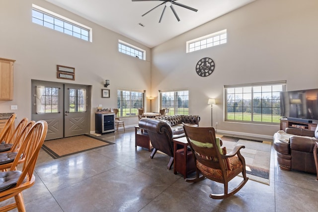 living area featuring a ceiling fan, baseboards, a wealth of natural light, and finished concrete floors