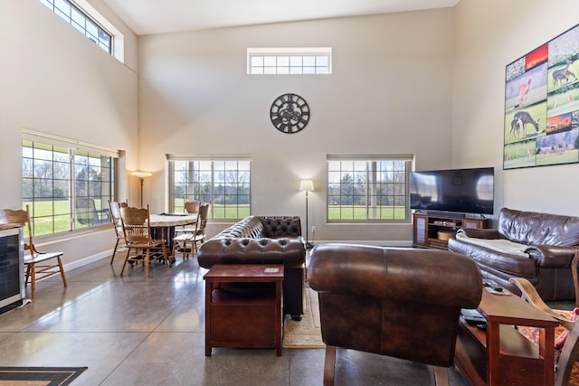 living area featuring a high ceiling, baseboards, and concrete floors