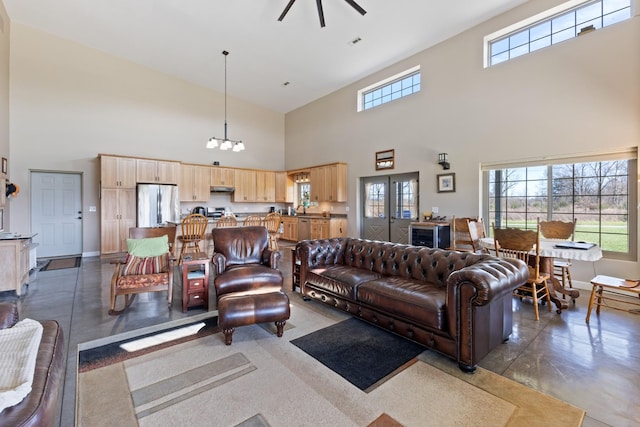 living room with ceiling fan with notable chandelier, concrete flooring, and baseboards