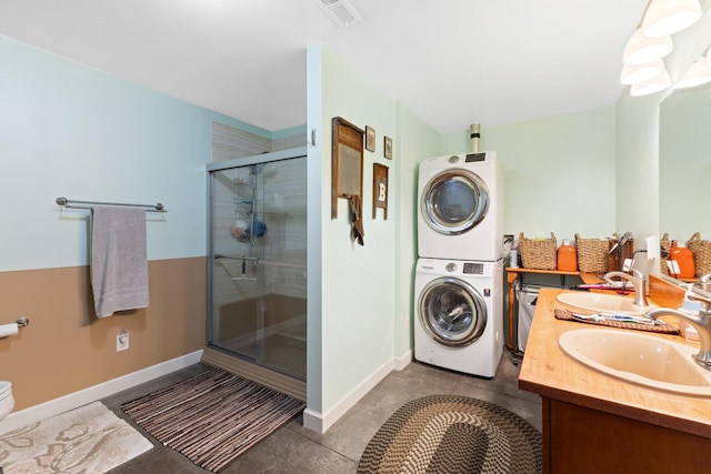 bathroom with double vanity, stacked washer and dryer, a stall shower, and a sink