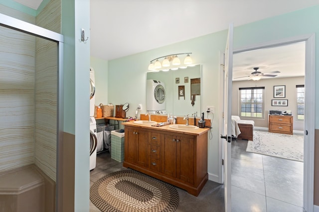 full bath featuring a ceiling fan, a sink, stacked washer and clothes dryer, tile patterned floors, and connected bathroom