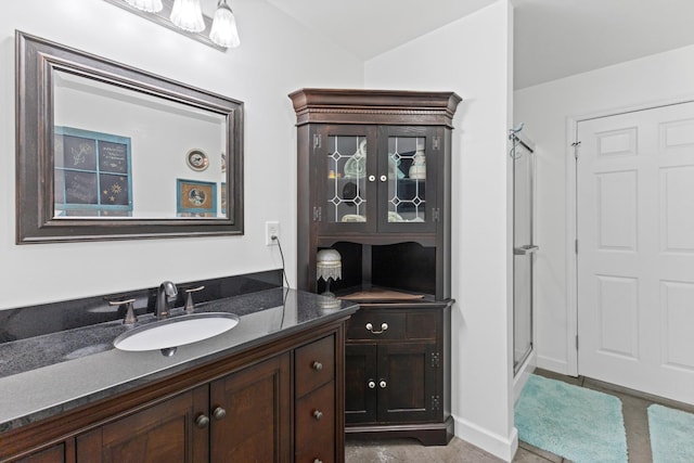 full bathroom with a stall shower, vanity, and baseboards