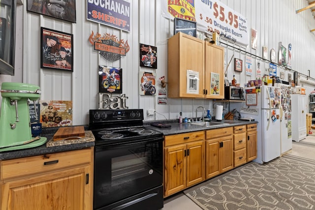 kitchen featuring stainless steel microwave, freestanding refrigerator, brown cabinetry, black electric range oven, and a sink