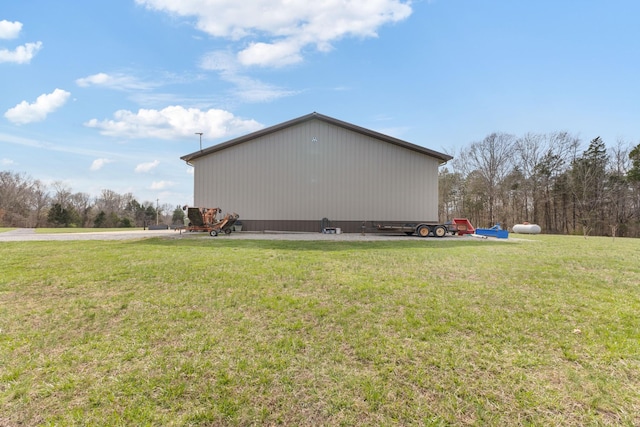 view of side of property featuring an outbuilding, a yard, and a pole building