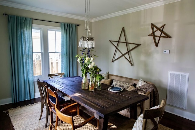 dining room featuring visible vents, crown molding, baseboards, and wood finished floors