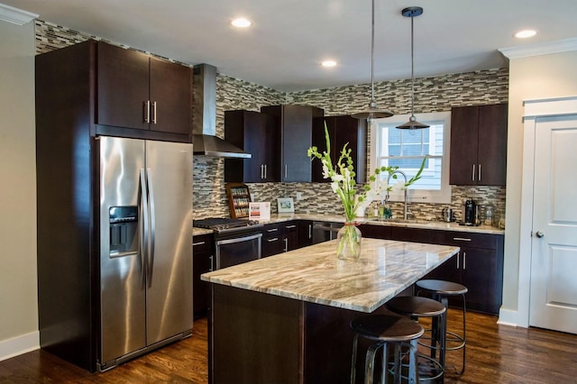 kitchen with a sink, backsplash, appliances with stainless steel finishes, wall chimney range hood, and dark wood-style flooring